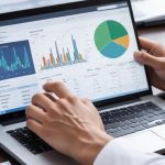 Hands analyzing financial charts on a laptop screen