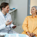 Male dentist consulting senior woman in dental clinic