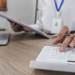 Close up Business woman using calculator and laptop for do math finance on wooden desk in office and