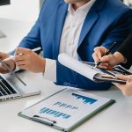 The business team analyzes revenue charts and graphs with laptop and tablet.Business analysis and strategic ideas.