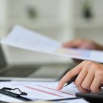Professional businessman checking finances and counting bills or taxes at office desk