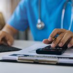 Doctor with calculate medical fee costs and revenue.