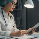 Nurse reviewing chart on tablet at desk