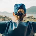surgeon standing outdoors with water and mountain scenery