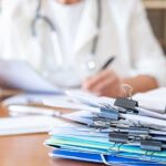 Healthcare professional checking medical documents, preparing paperwork, and managing administrative tasks related to patient care and health information in a clinic or office setting